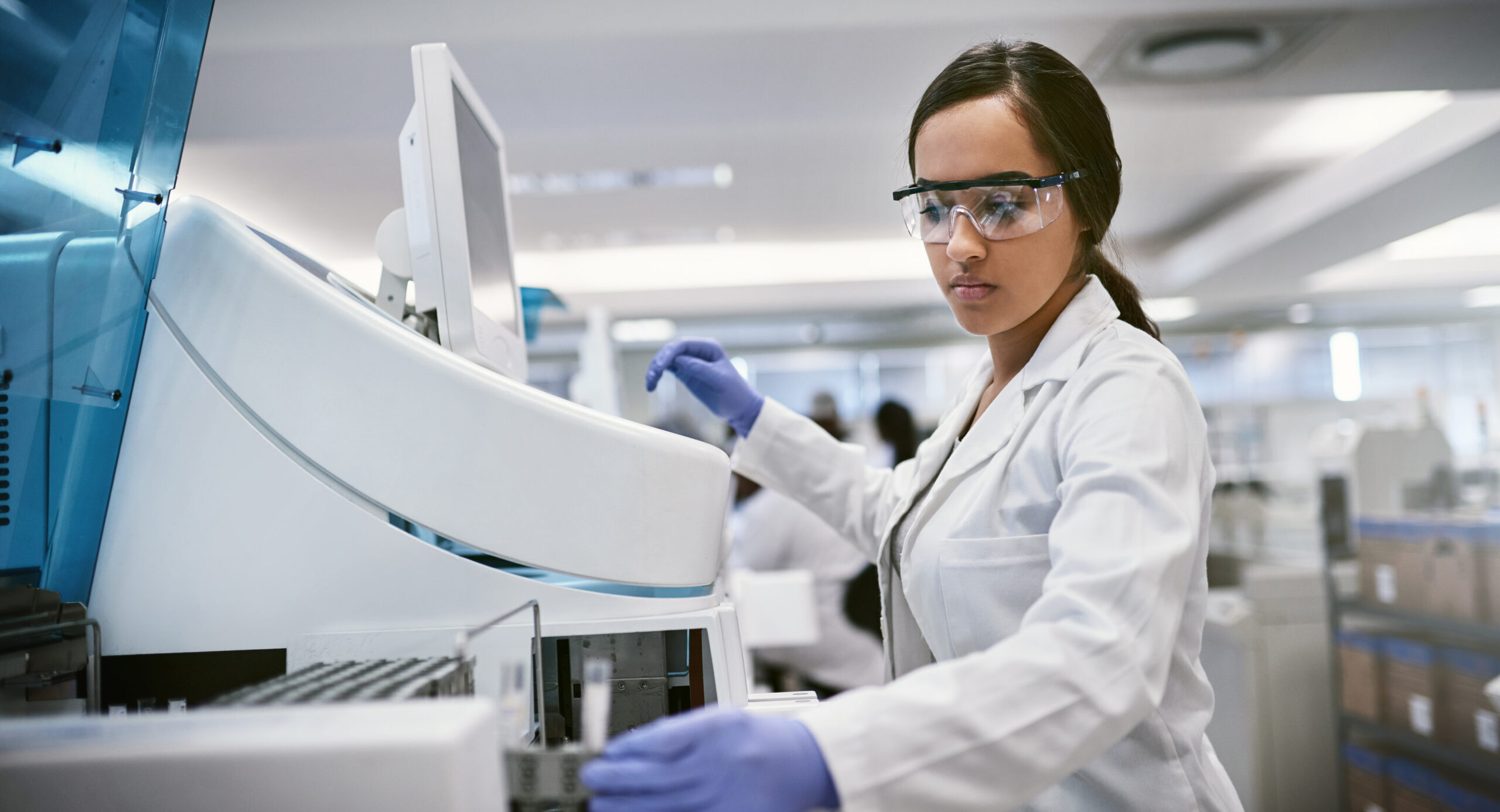 Shot of a young woman using a machine to conduct a medical test in a laboratory