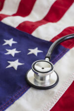 A close-up of a stethoscope resting on an American flag, symbolizing the connection between healthcare and the United States.